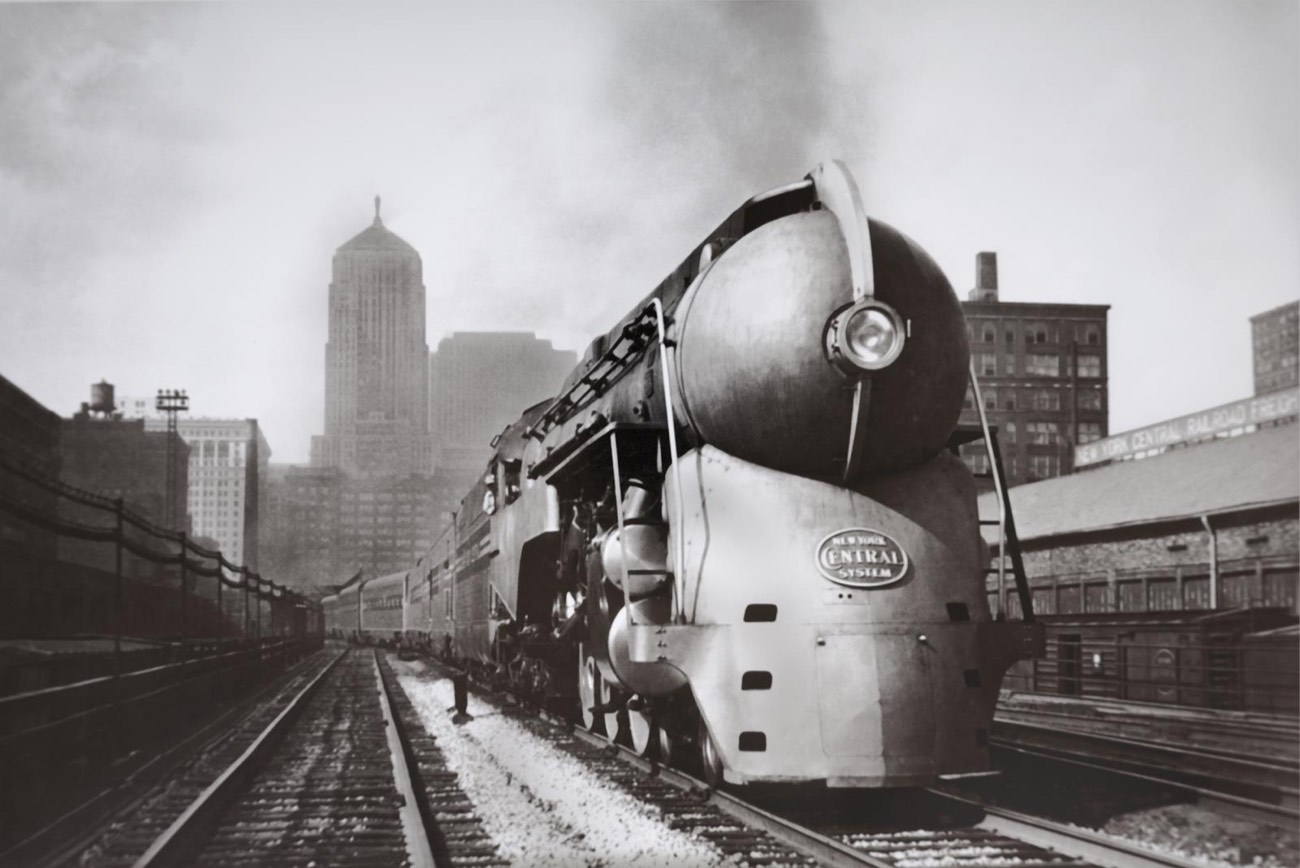 Archival photograph of a streamlined steam locomotive with the Chicago skyline behind it