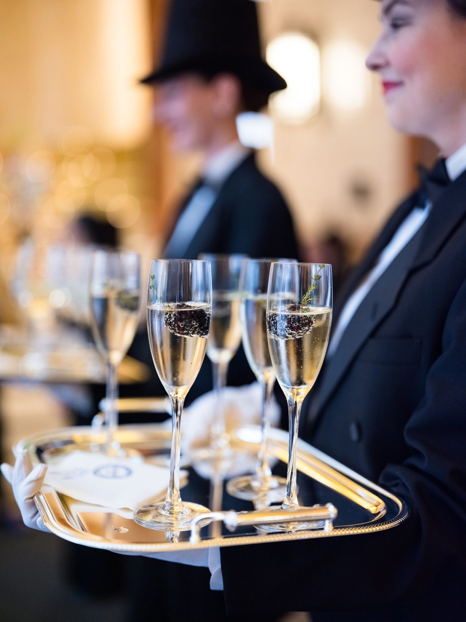 Servers offering champagne from a gold tray