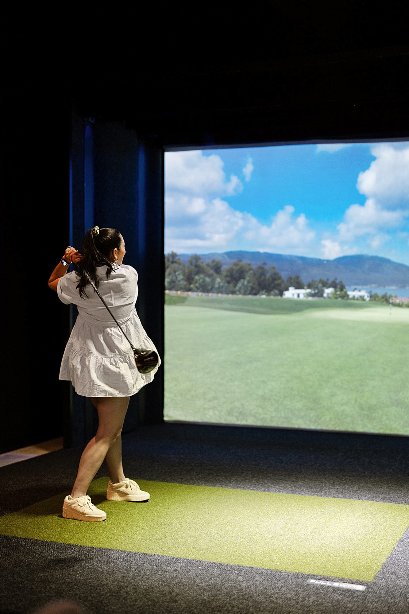 A guest taking a swing at the golf simulator