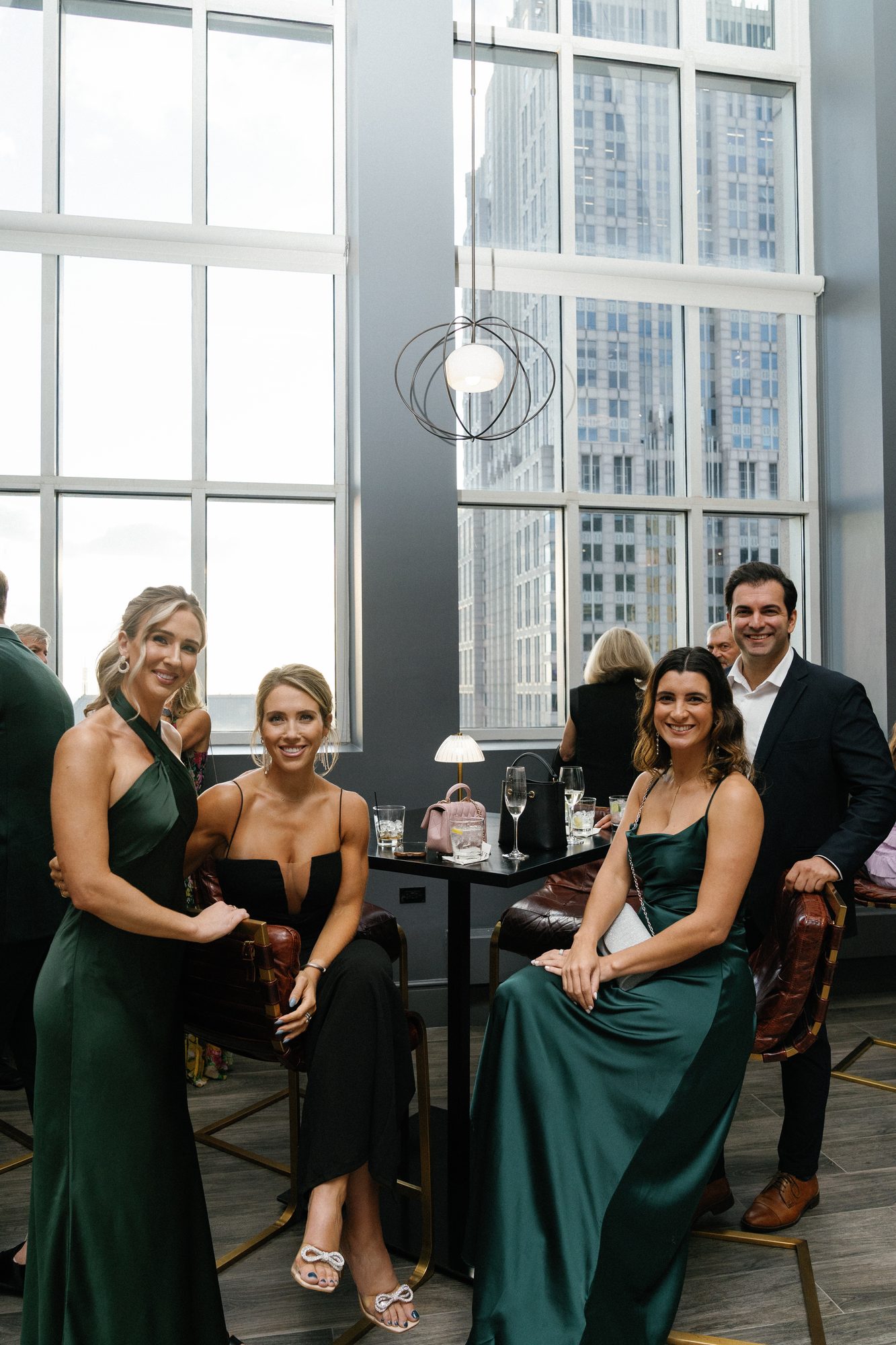 Bridesmaids and guests gathered by the tall windows