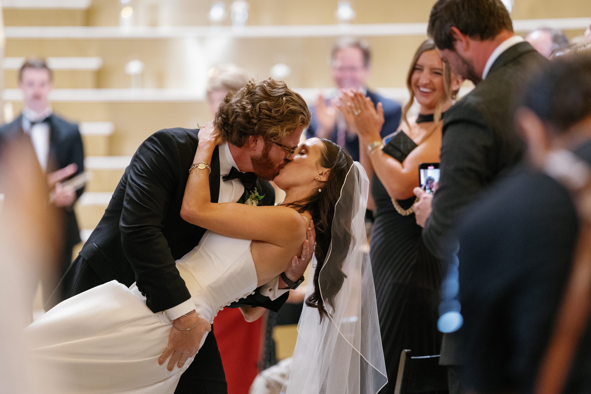 A couple sharing a kiss as guests cheer